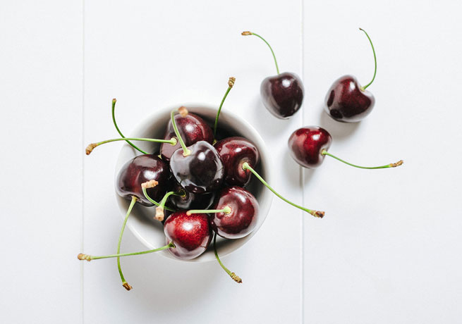 Bowl of Kordia cherries on a table top.